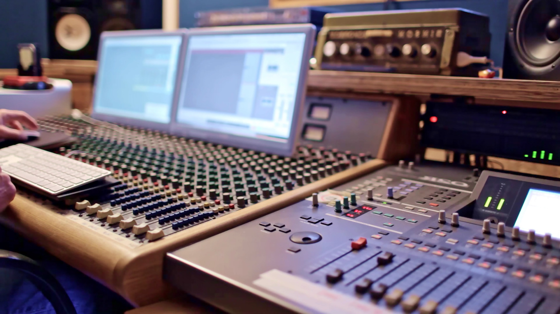 Sound engineer monitoring audio mixer in audio recording studio